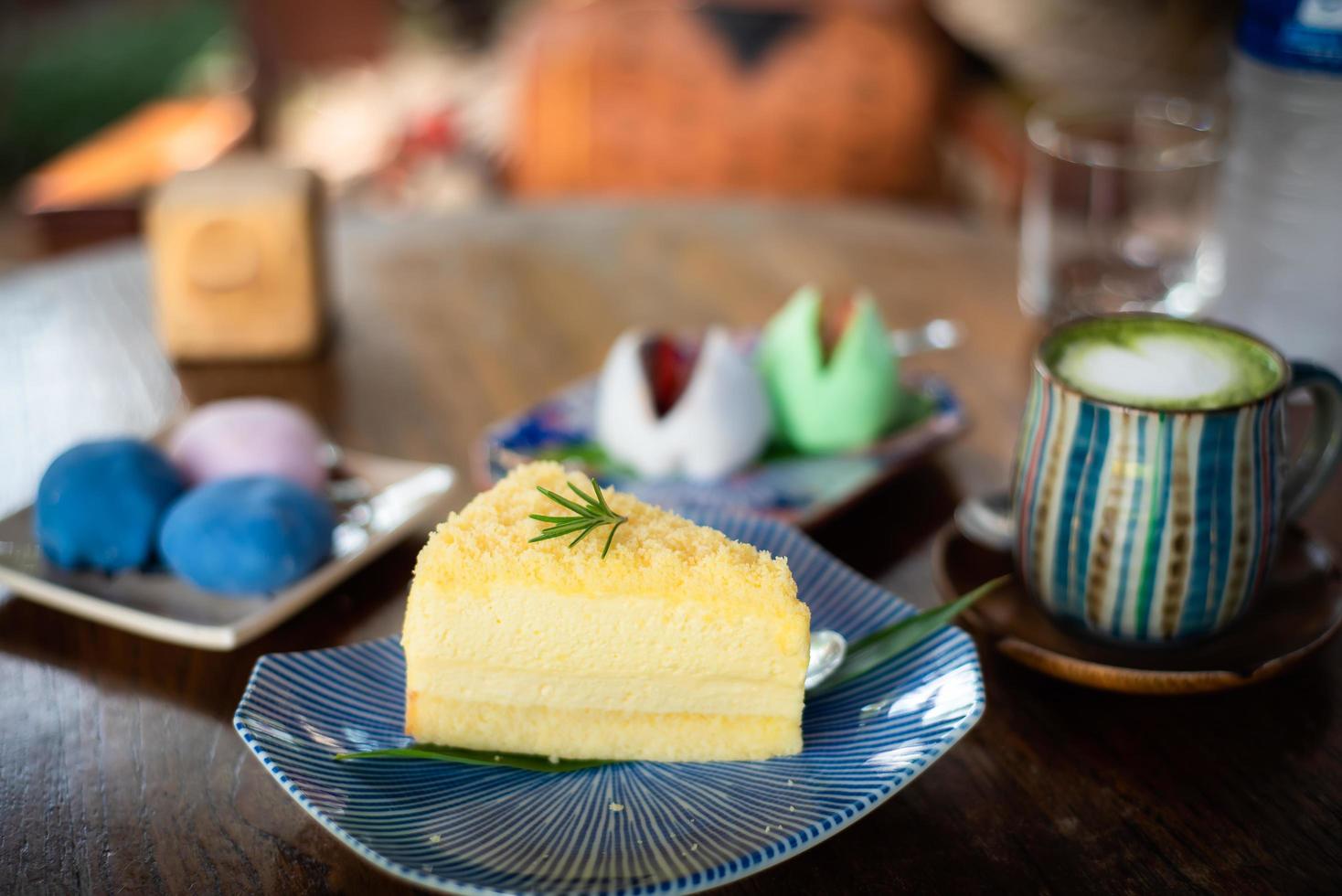 Close-up Cream cheese chiffon cake in a tiled plate decorated with rosemary leaves and Matcha green tea on top decorated latte art with heart-shaped milk foam in a colorful cup, Japanese style cake photo