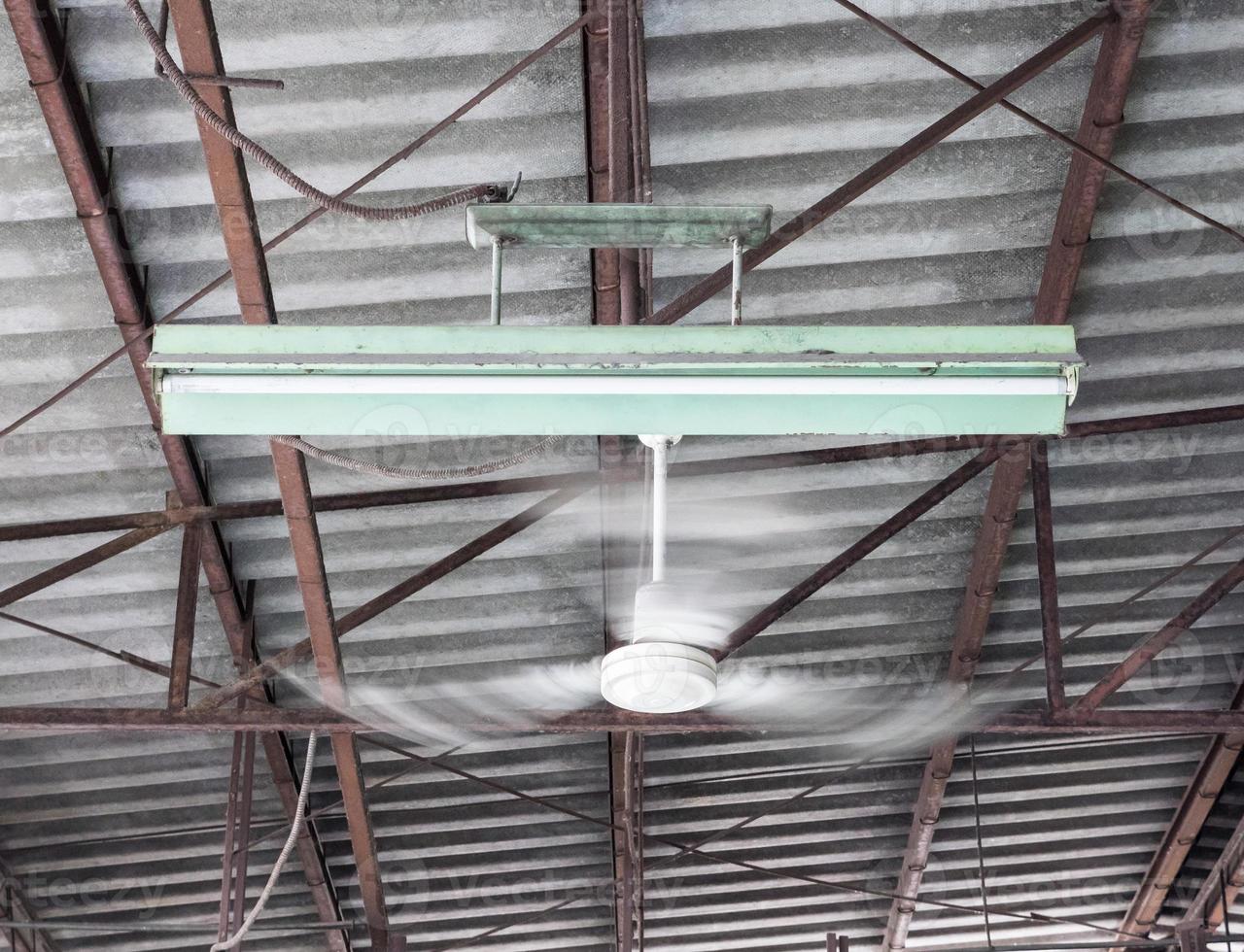 Old ceiling fan is moving near the electric lamp. photo