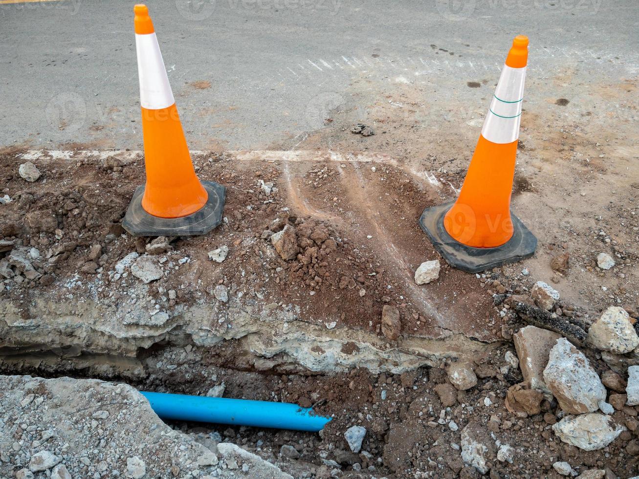 The new PVC pipe is laying in the trench near the asphalt road for the water supply system. photo