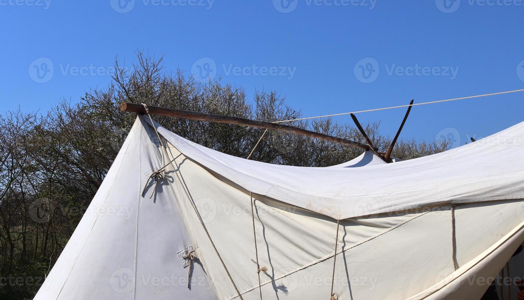 antigua tienda vikinga hecha de madera y tela frente a un cielo azul foto