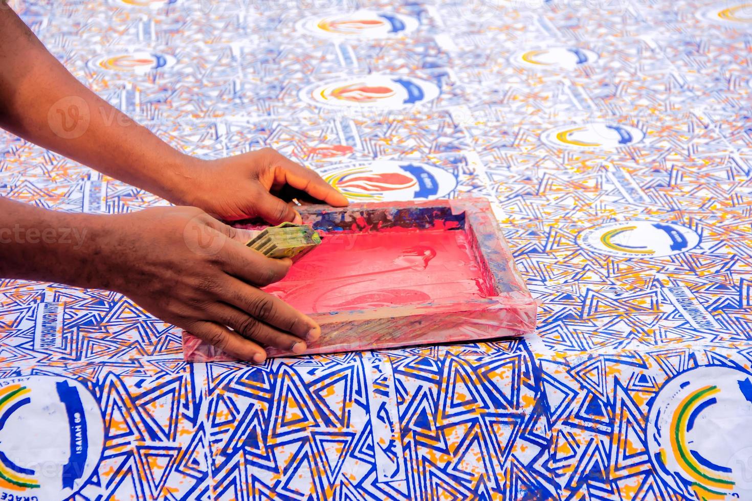 Hand an artist pressing squeegee on a screen printing box to print on cloth. photo