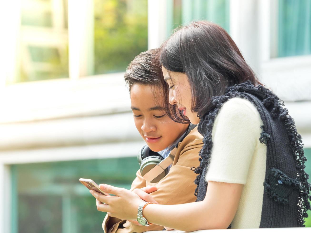 Young boy and girl play games on mobile phones photo