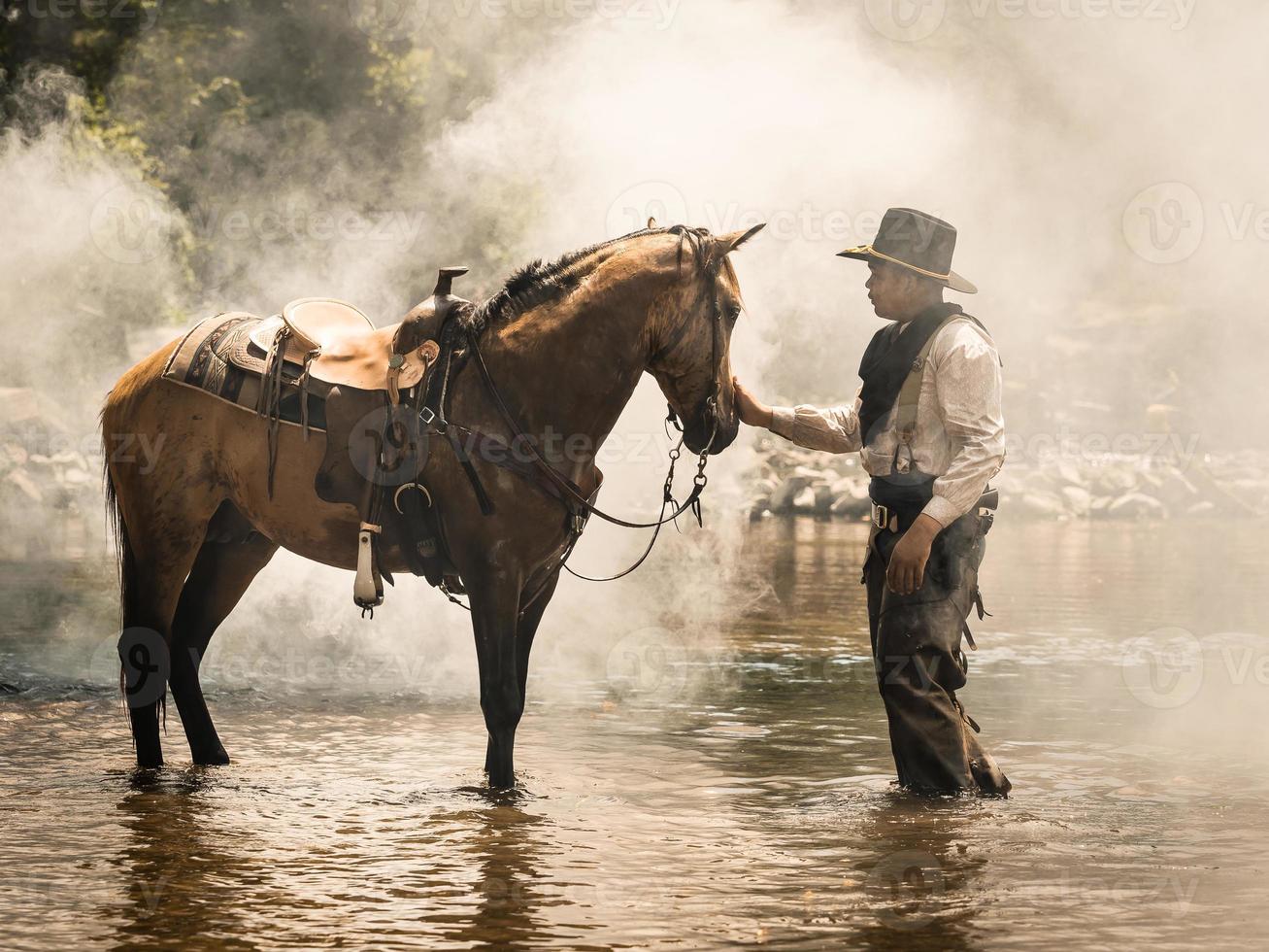 A young cowboy rested with a horse in the stream after he finished showering the horse photo