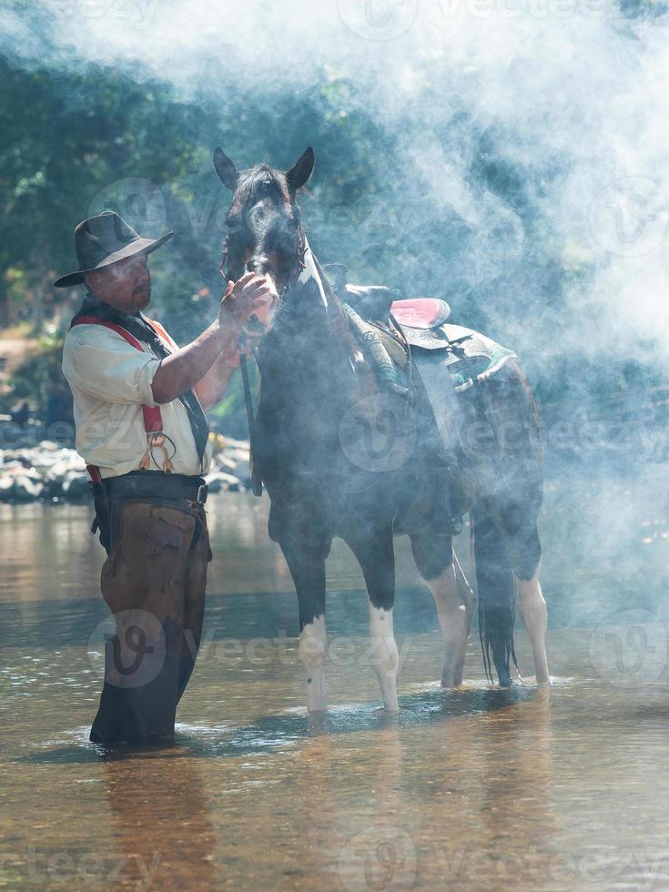 vaqueros mayores descansando con caballos y se pusieron a bañarse en el río foto