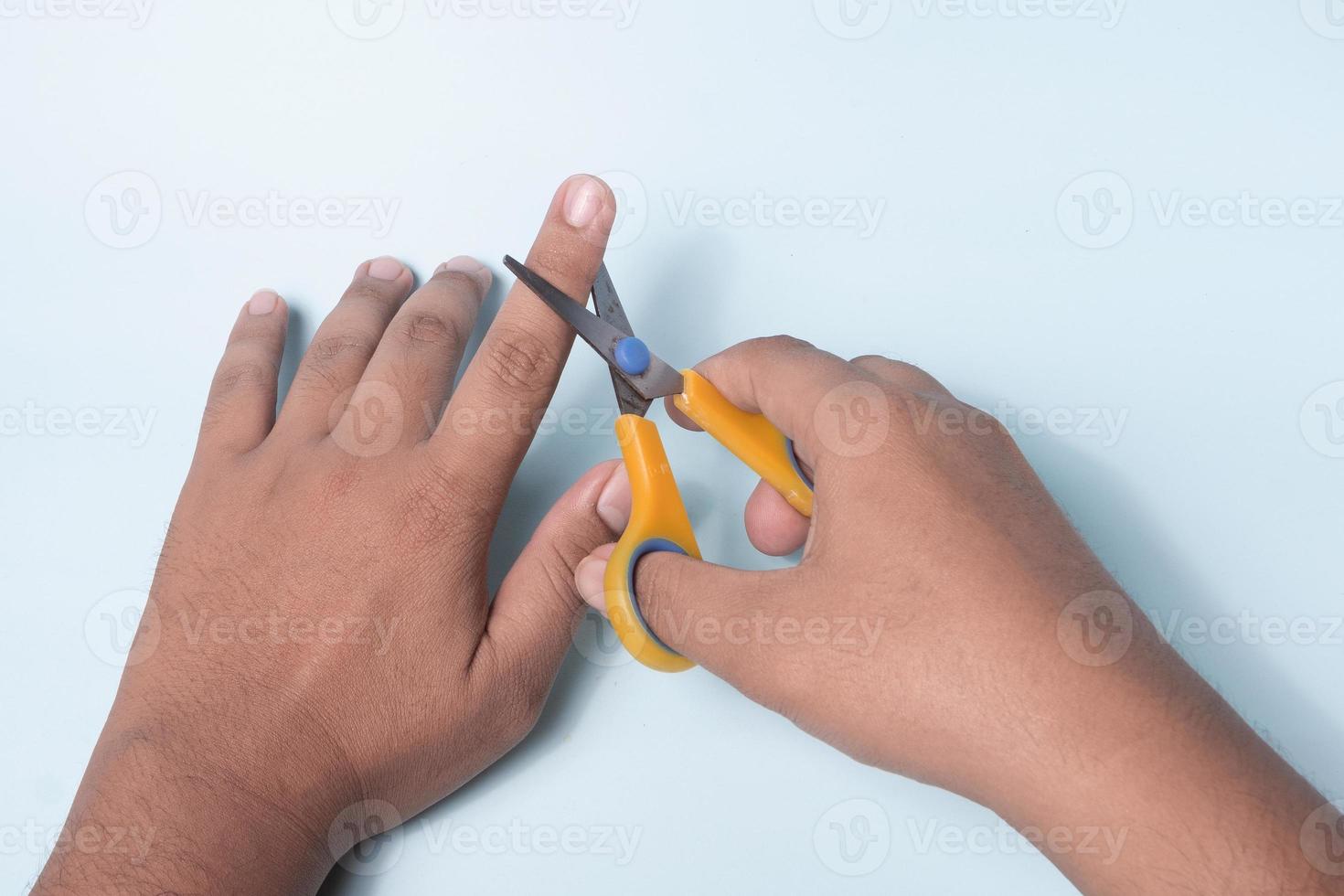a man's hand is trying to cut a finger using scissors photo