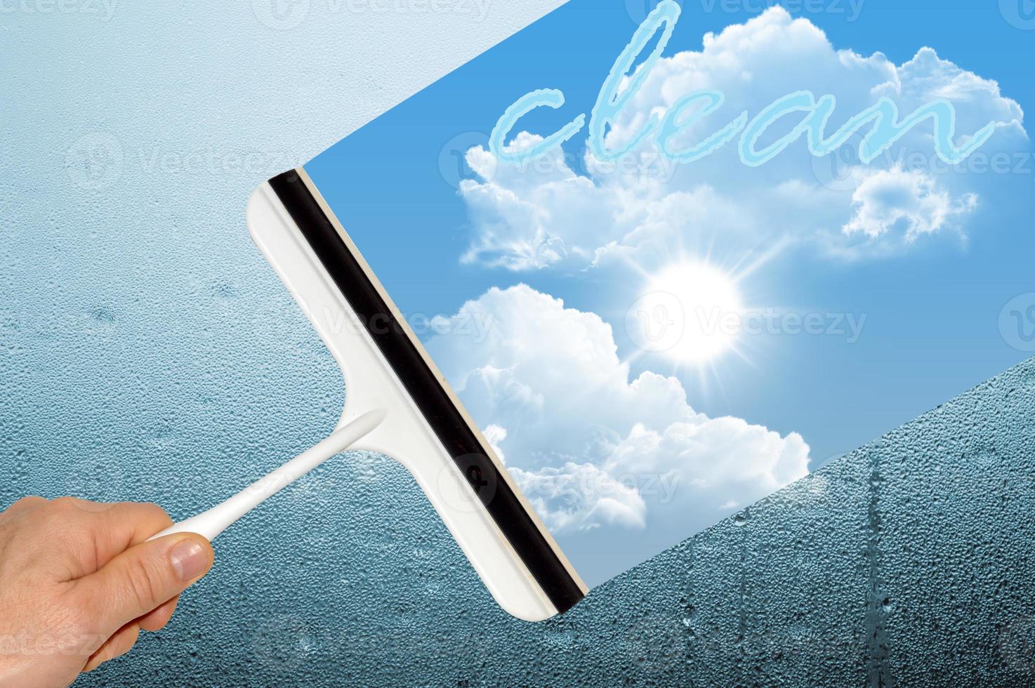 hand with squeegee cleaning misted glass photo