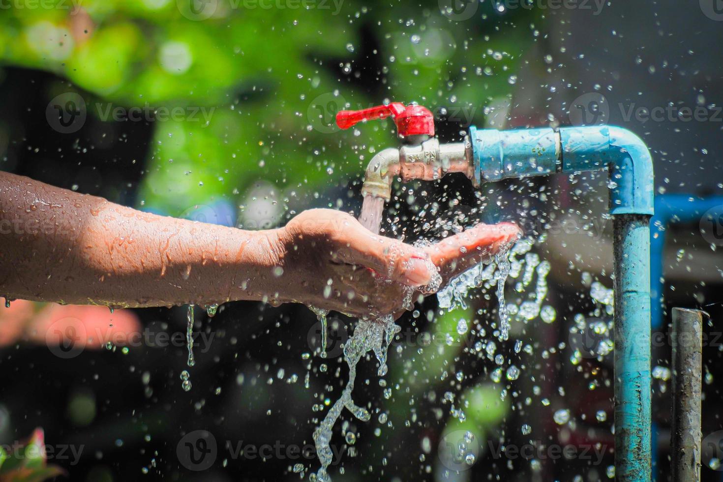 Water concept in everyday life. Hands supporting the water flowing from the faucet. water splashing from the tap photo