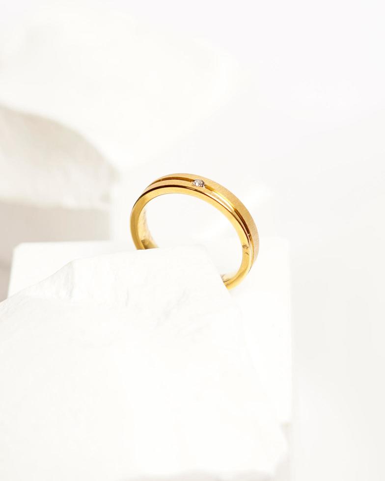 Diamond jewelery ring for social media display. Wedding ring photographed on white stone. Engagement ring with gemstones. Wedding rings isolated on a bright white background, focus blur. Gold ring. photo