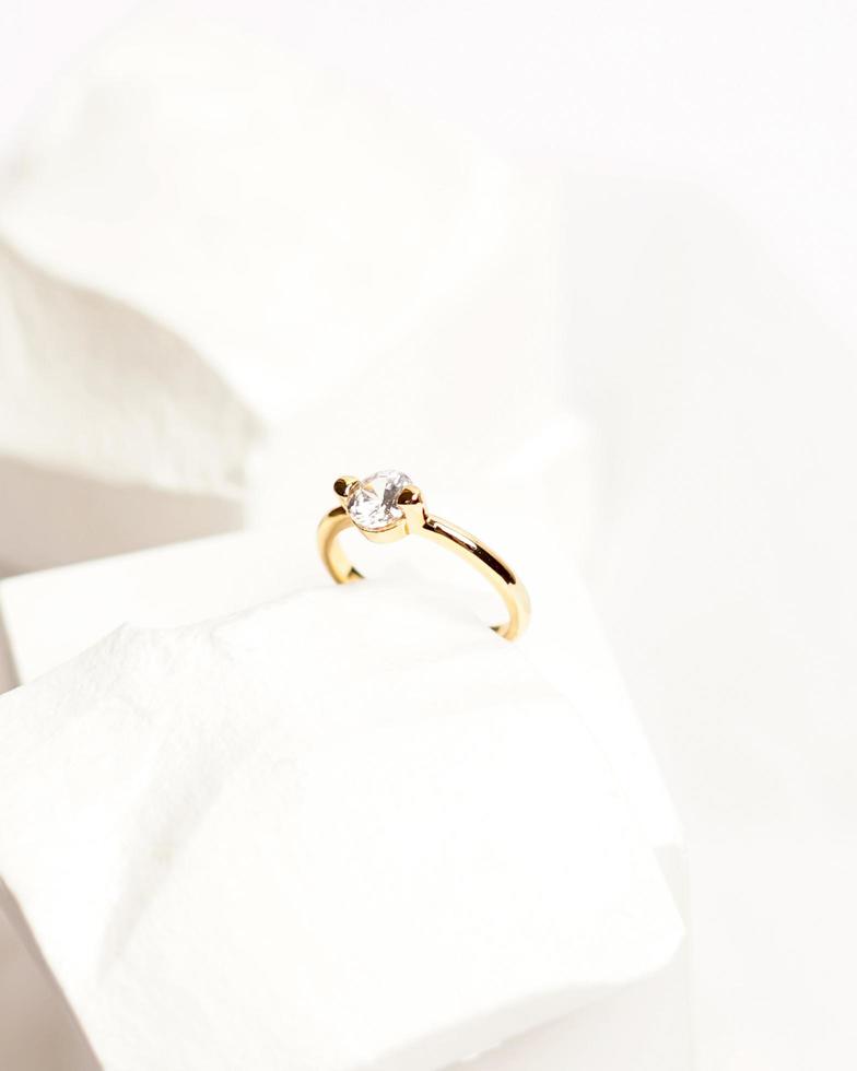 Diamond jewelery ring for social media display. Wedding ring photographed on white stone. Engagement ring with gemstones. Wedding rings isolated on a bright white background, focus blur. Gold ring. photo