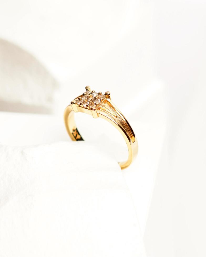 Diamond jewelery ring for social media display. Wedding ring photographed on white stone. Engagement ring with gemstones. Wedding rings isolated on a bright white background, focus blur. Gold ring. photo