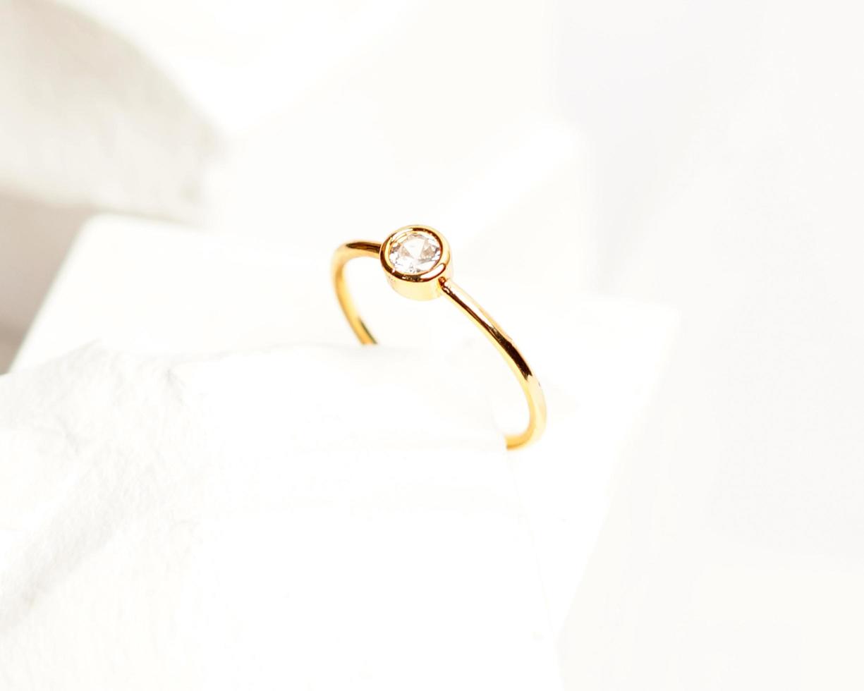 Diamond jewelery ring for social media display. Wedding ring photographed on white stone. Engagement ring with gemstones. Wedding rings isolated on a bright white background, focus blur. Gold ring. photo