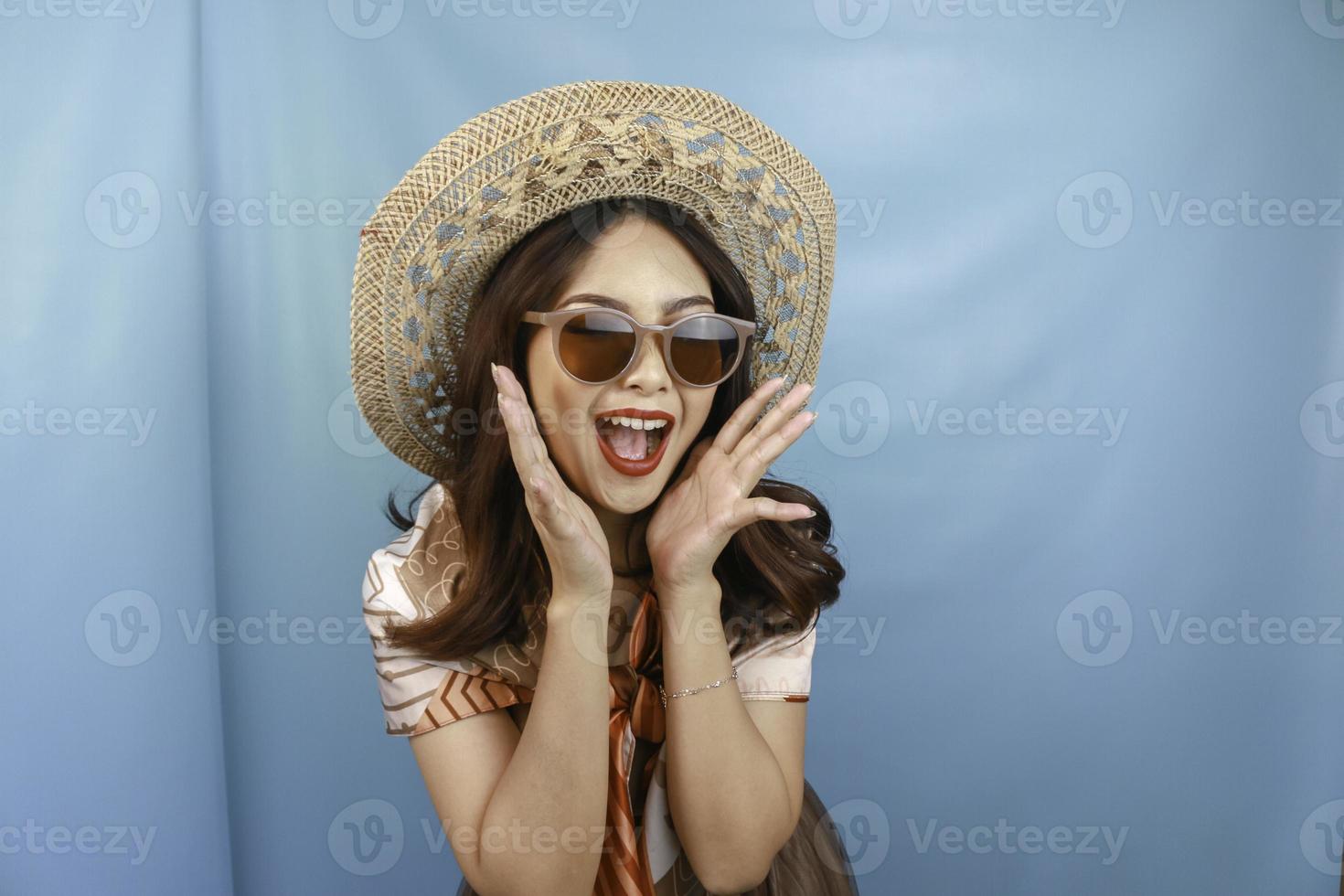 Young Asian shocked woman is yelling isolated by a blue background. photo