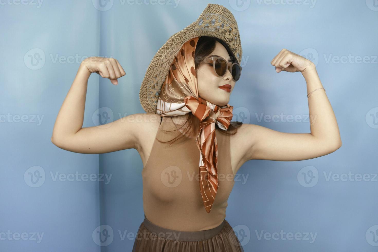 Young Asian strong woman showing her biceps isolated by a blue background photo