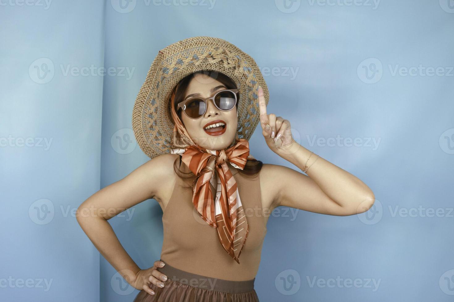 Young Asian happy woman isolated by a blue background pointing copy space upward. photo