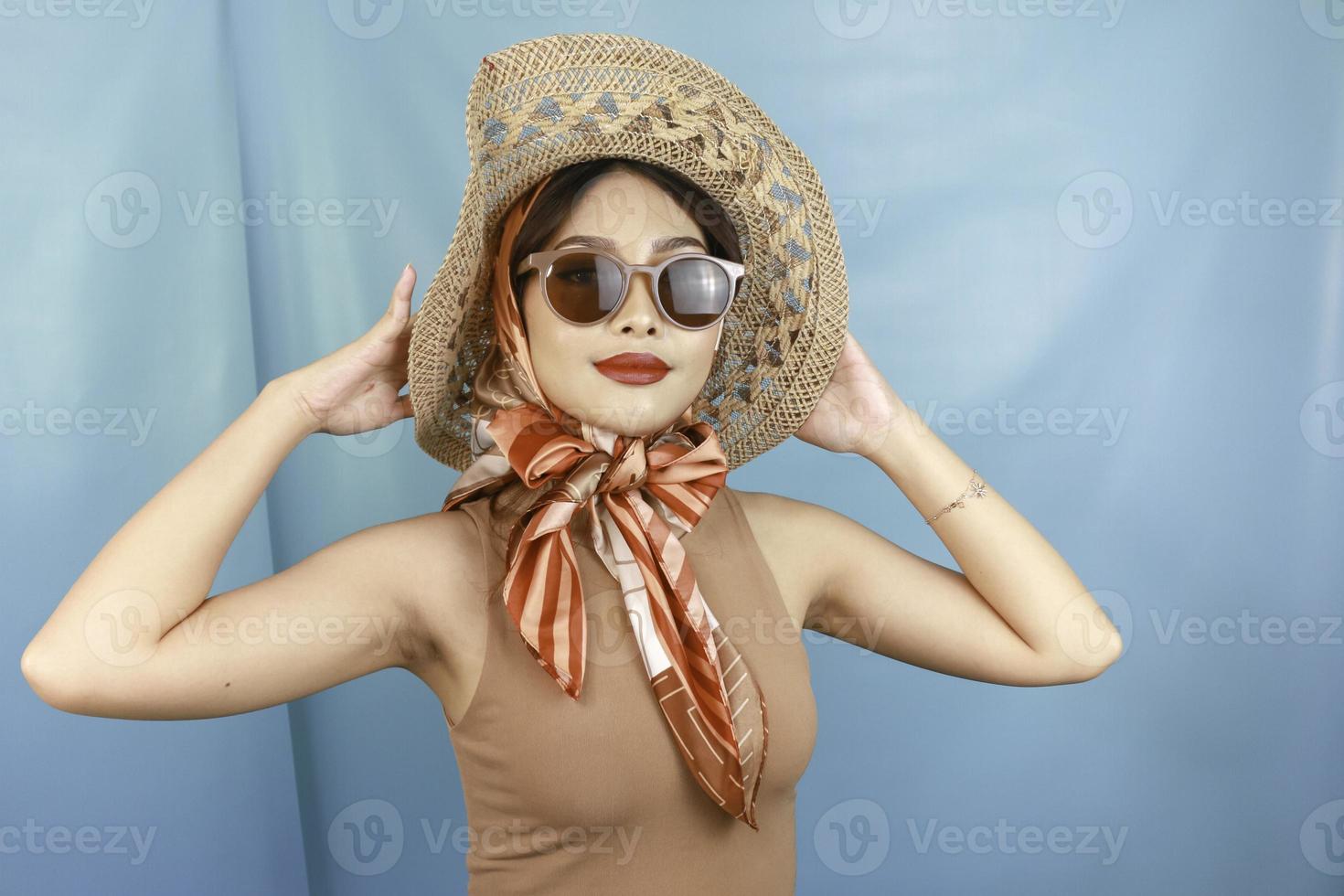 Traveling concept of a young Asian happy woman isolated by a blue background. photo