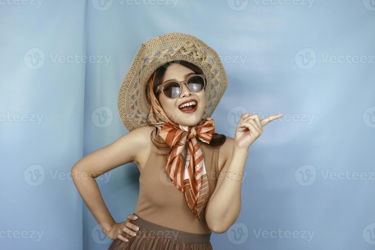 Young Asian happy woman isolated by a blue background pointing copy space on the side. photo