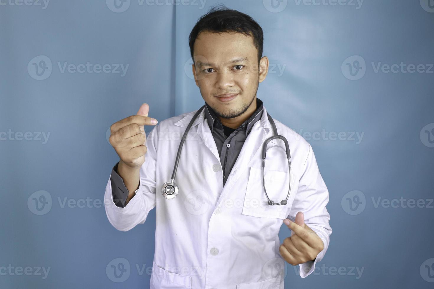 A portrait of a young Asian male doctor is showing heart finger or love gesture photo