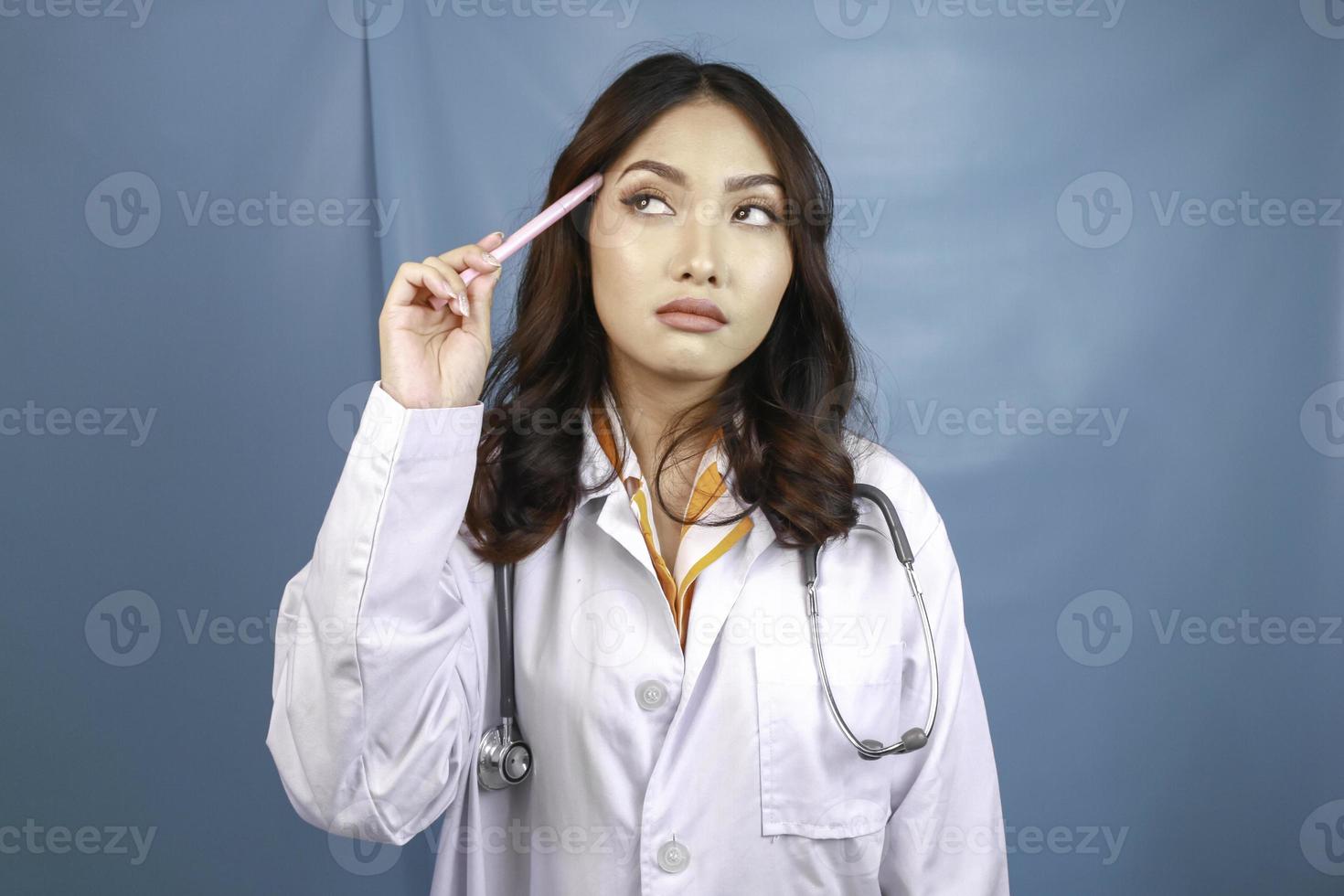 Young doctor woman over isolated background thinking an idea photo