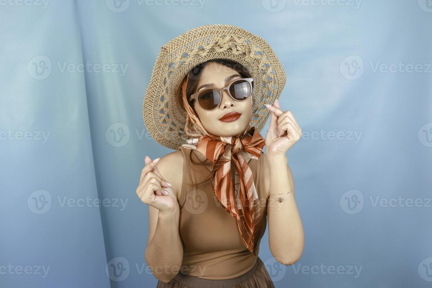 Traveling concept of a young Asian happy woman showing love or mini heart isolated by a blue background photo