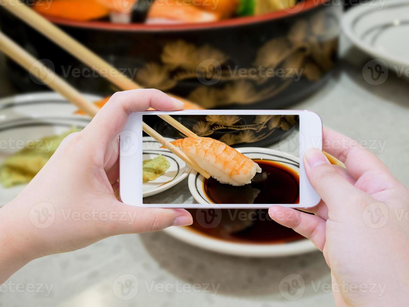 Taking photo of prawn sushi in chopsticks