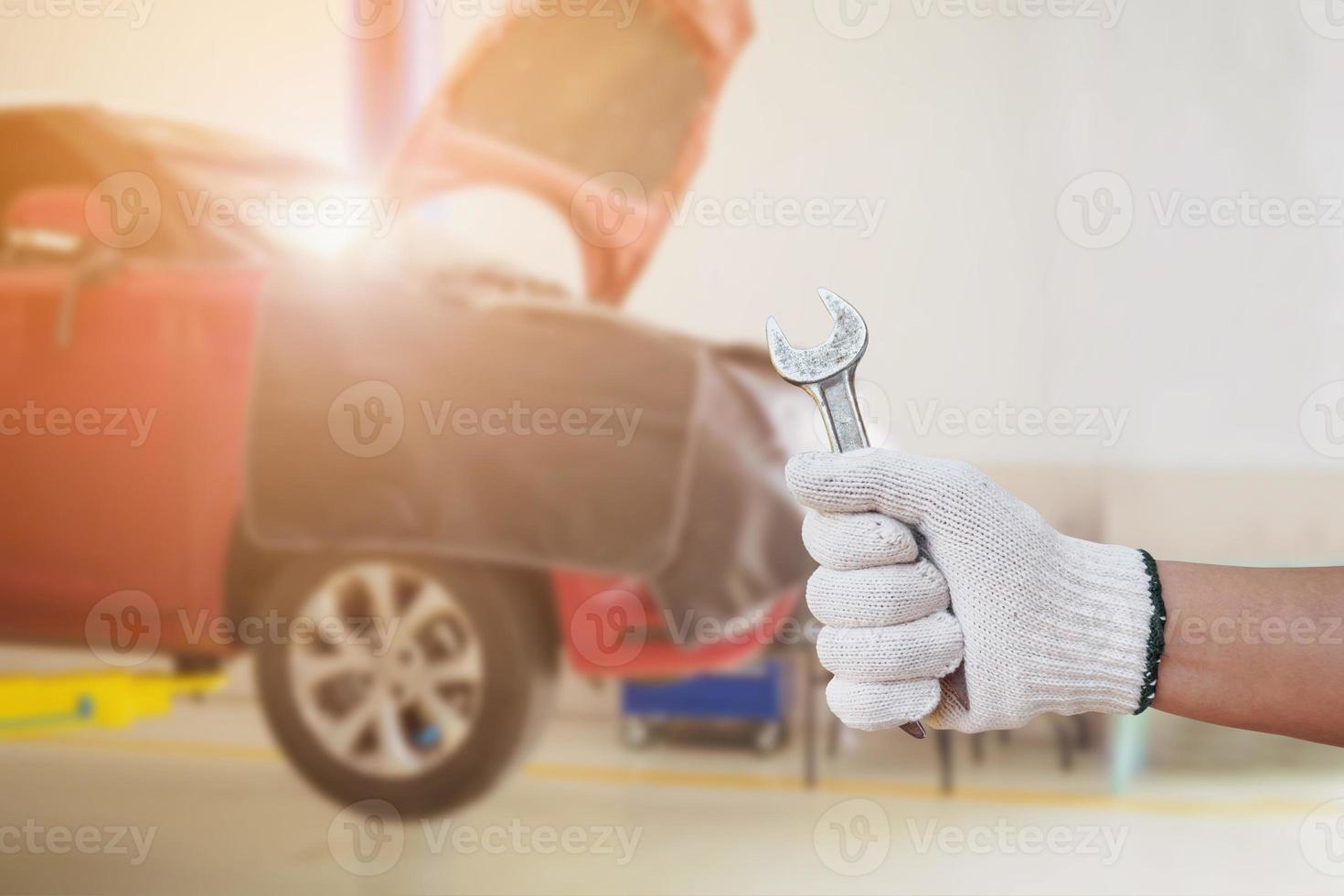 Car repair shop service centre, auto mechanic hand hold wrench working tool in garage photo