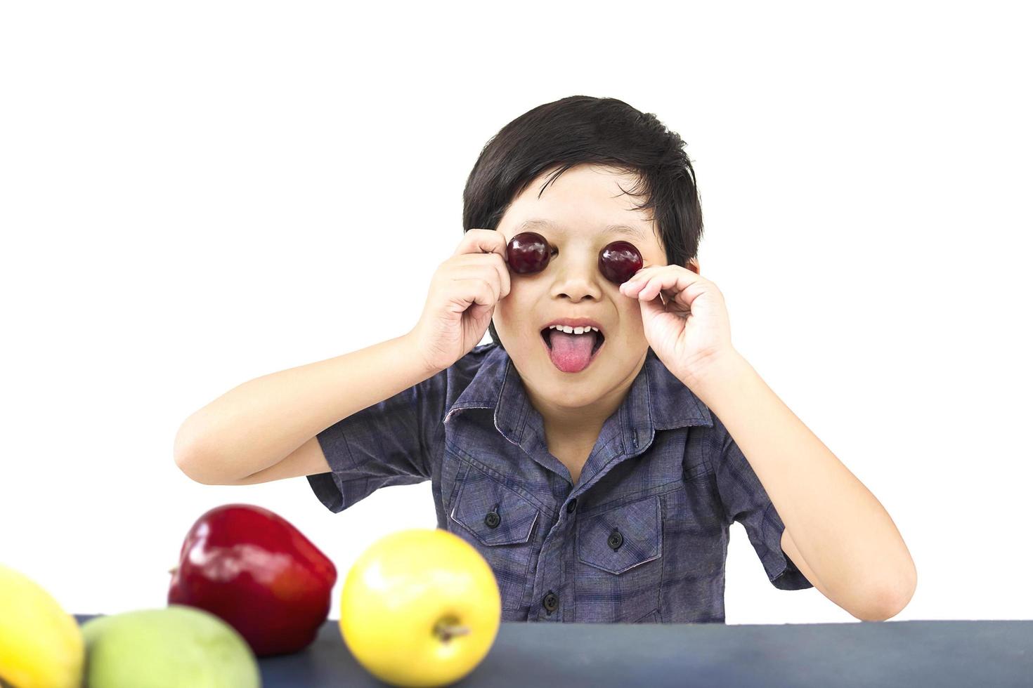 Asian healthy boy showing happy expression with variety colorful fruit and vegetable over white background photo