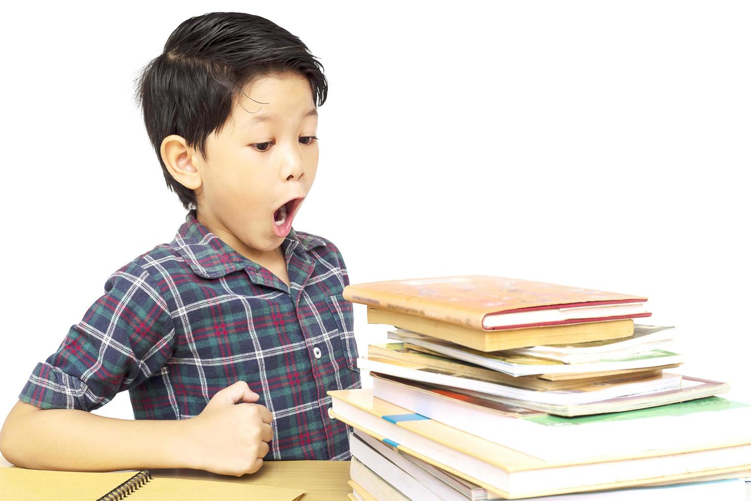 Asian boy is shouting while looking at a pile of book isolated over white background photo
