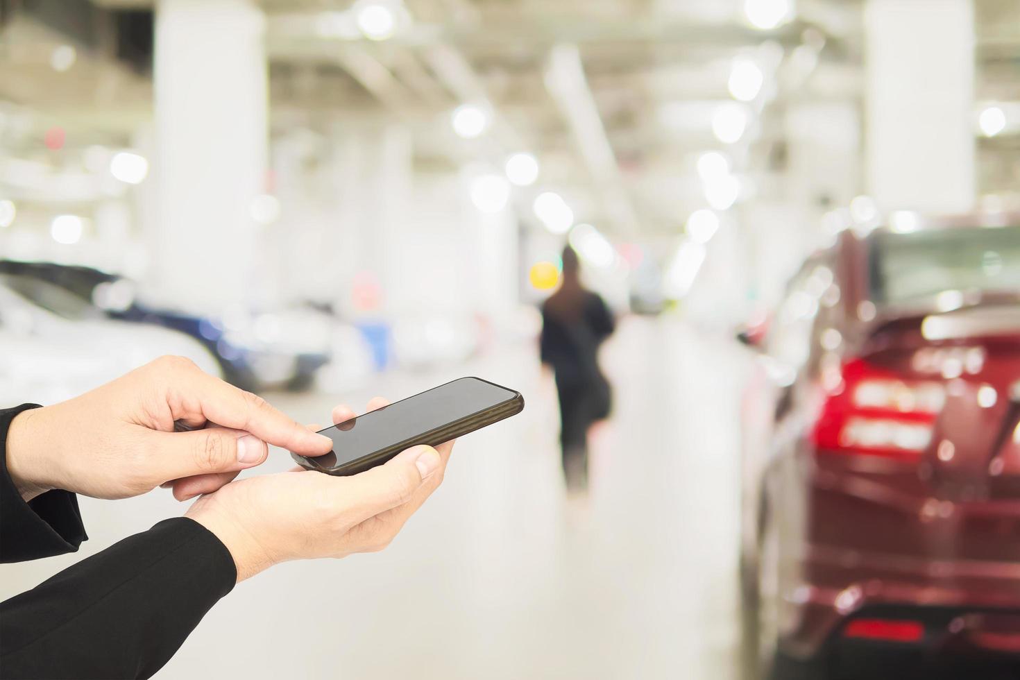 Hand is using telephone over blurred photo of a woman is walking dangerously in a car parking area