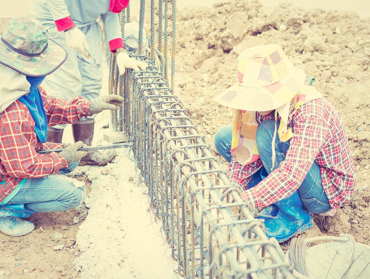 Vintage style photo of construction workers are installing steel rods in reinforced concrete beam