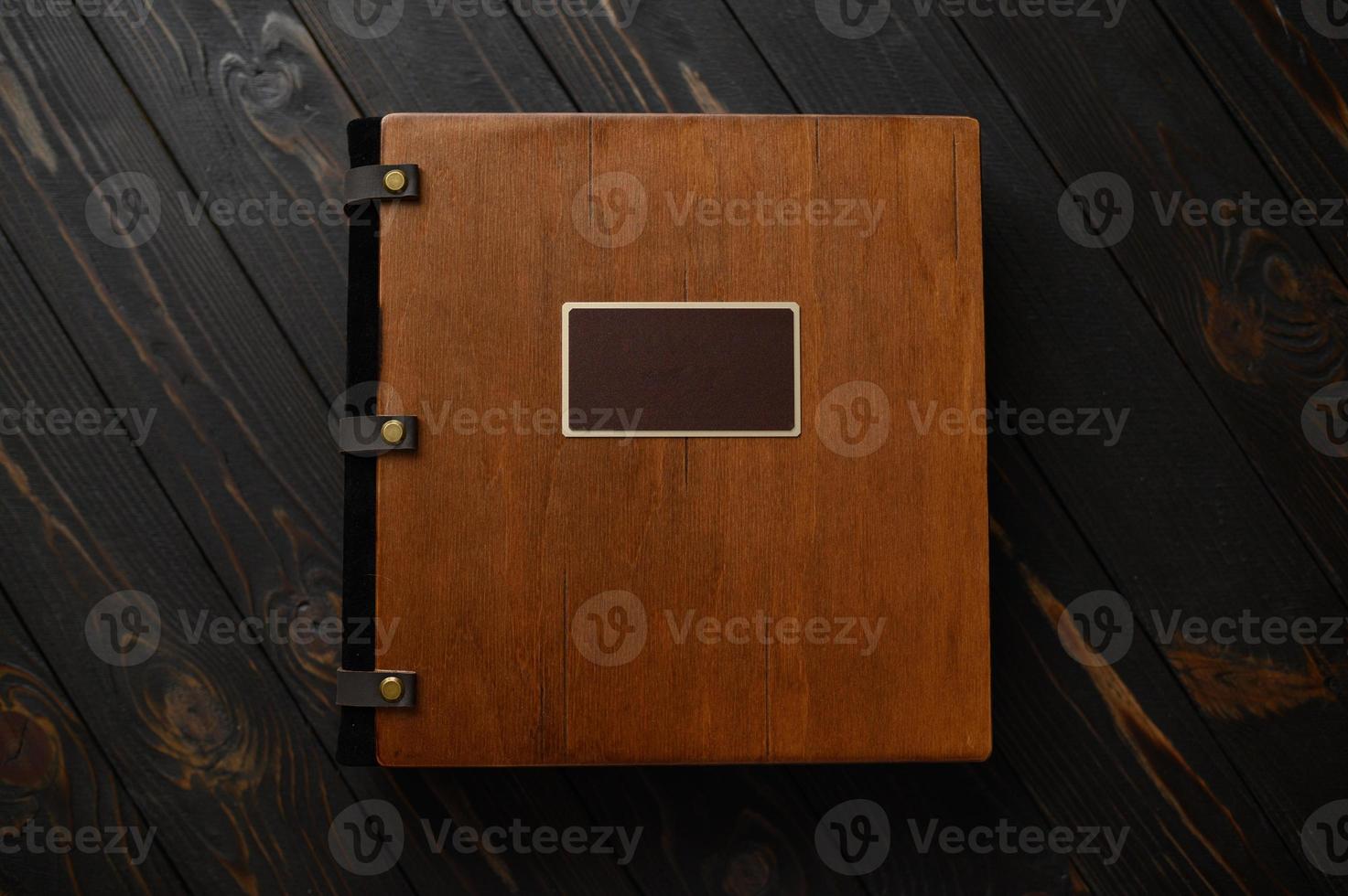 An old photo album with a wooden cover and a shield on a rustic table. free logo