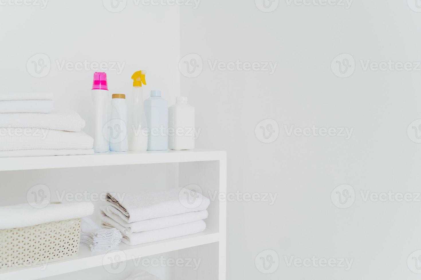 Stack of white soft towels with soft conditioner liquid. White background with copy space for your information. Cleanliness concept. Natural light photo