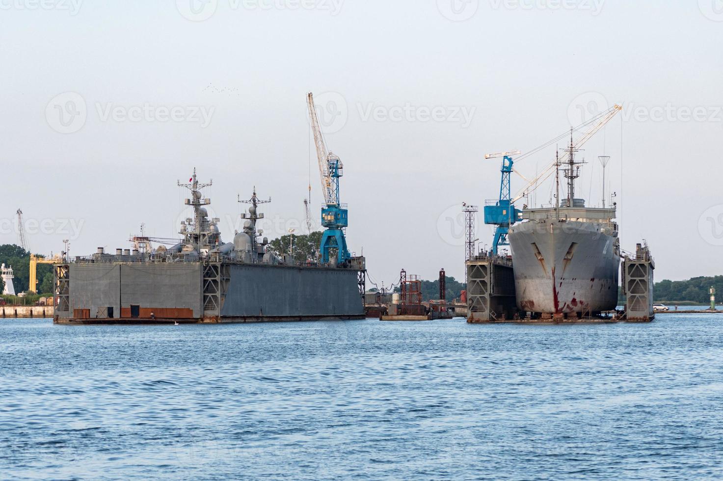 Large iron navy ships in shipyard for repair. Big crane in dockyard. Blue sea harbor photo