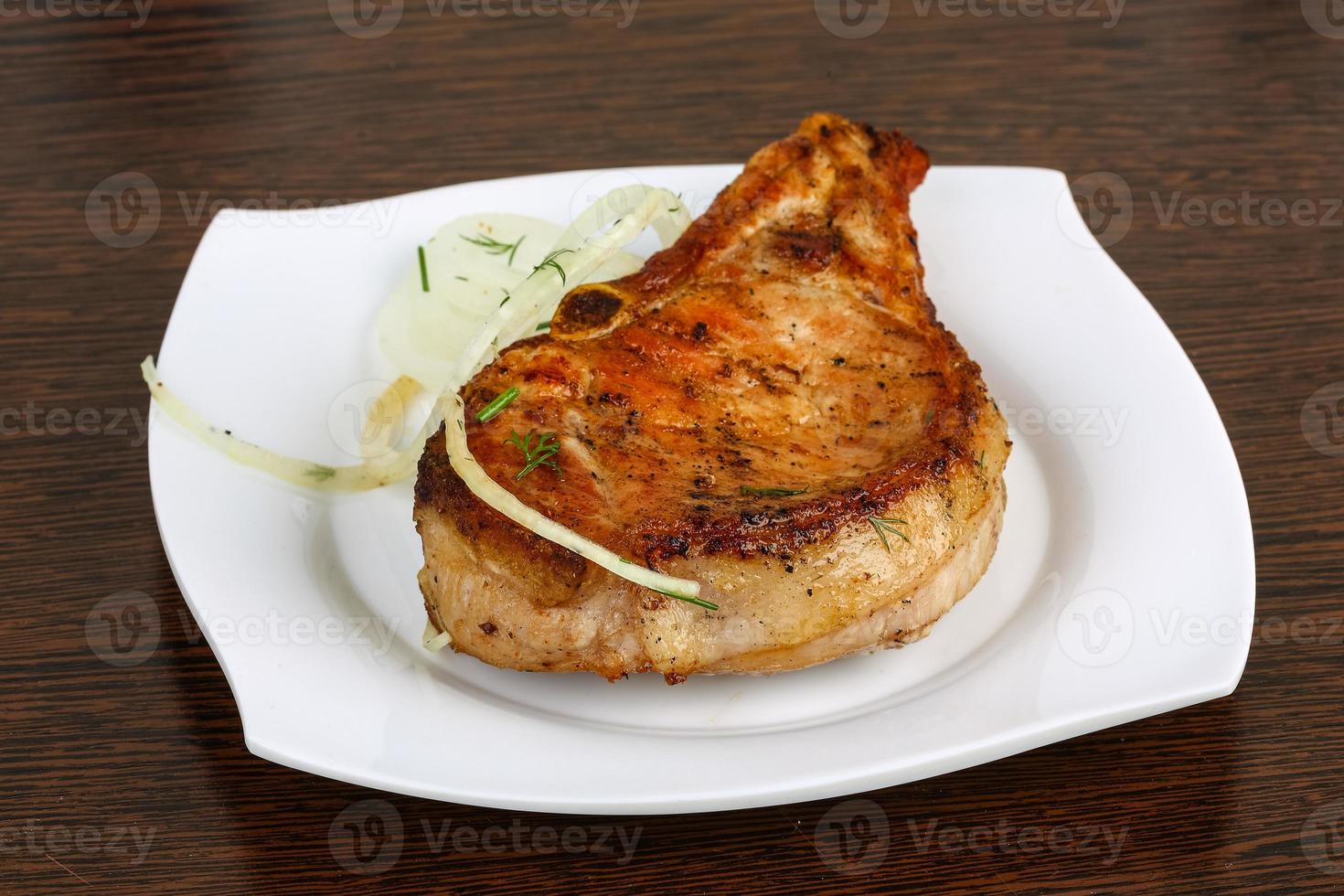 Grilled pork on the plate and wooden background photo