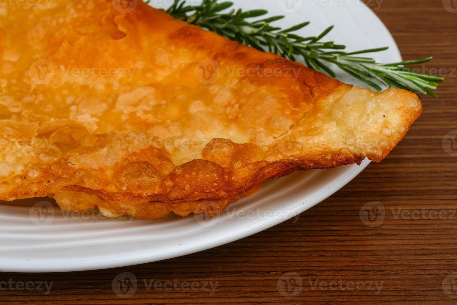 Meat Cheburek on the plate and wooden background photo