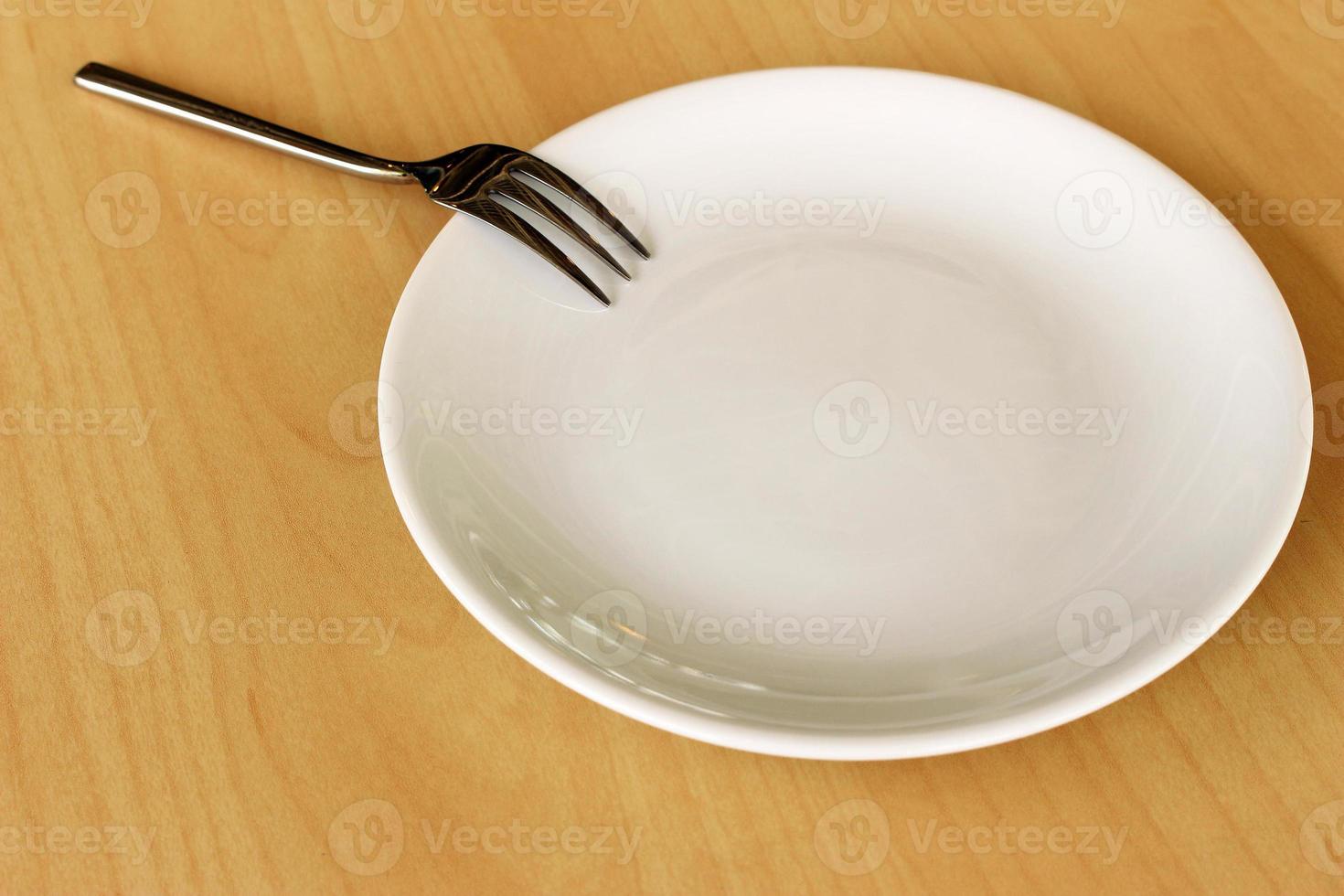 Empty plate and fork on wood table photo