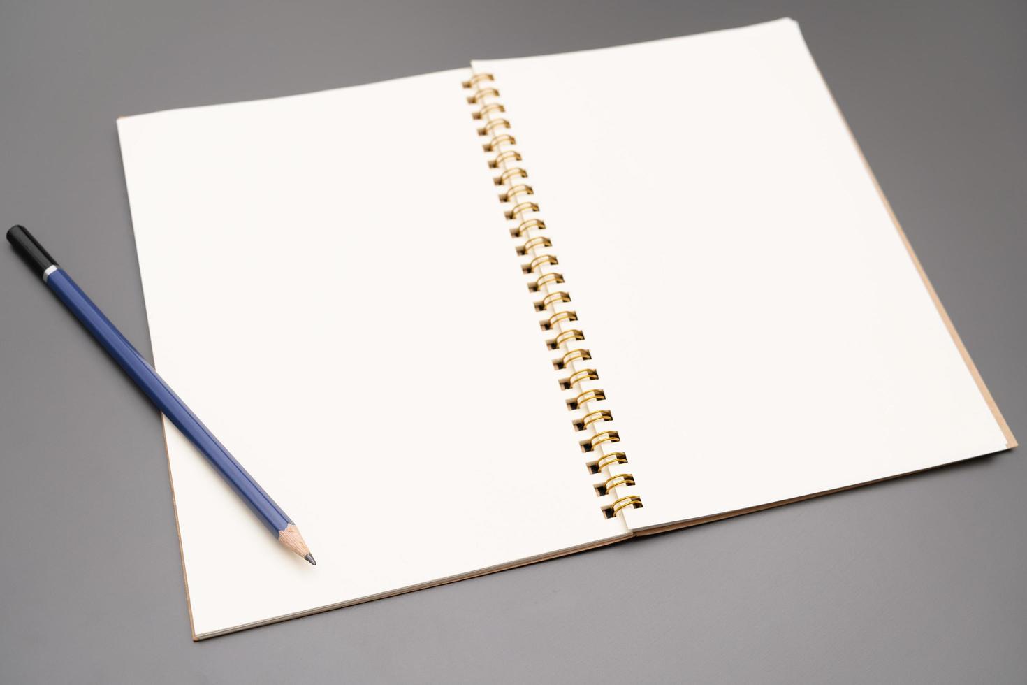Notebook with a pencil. open spiral blank notebook with pencil on white desk background photo