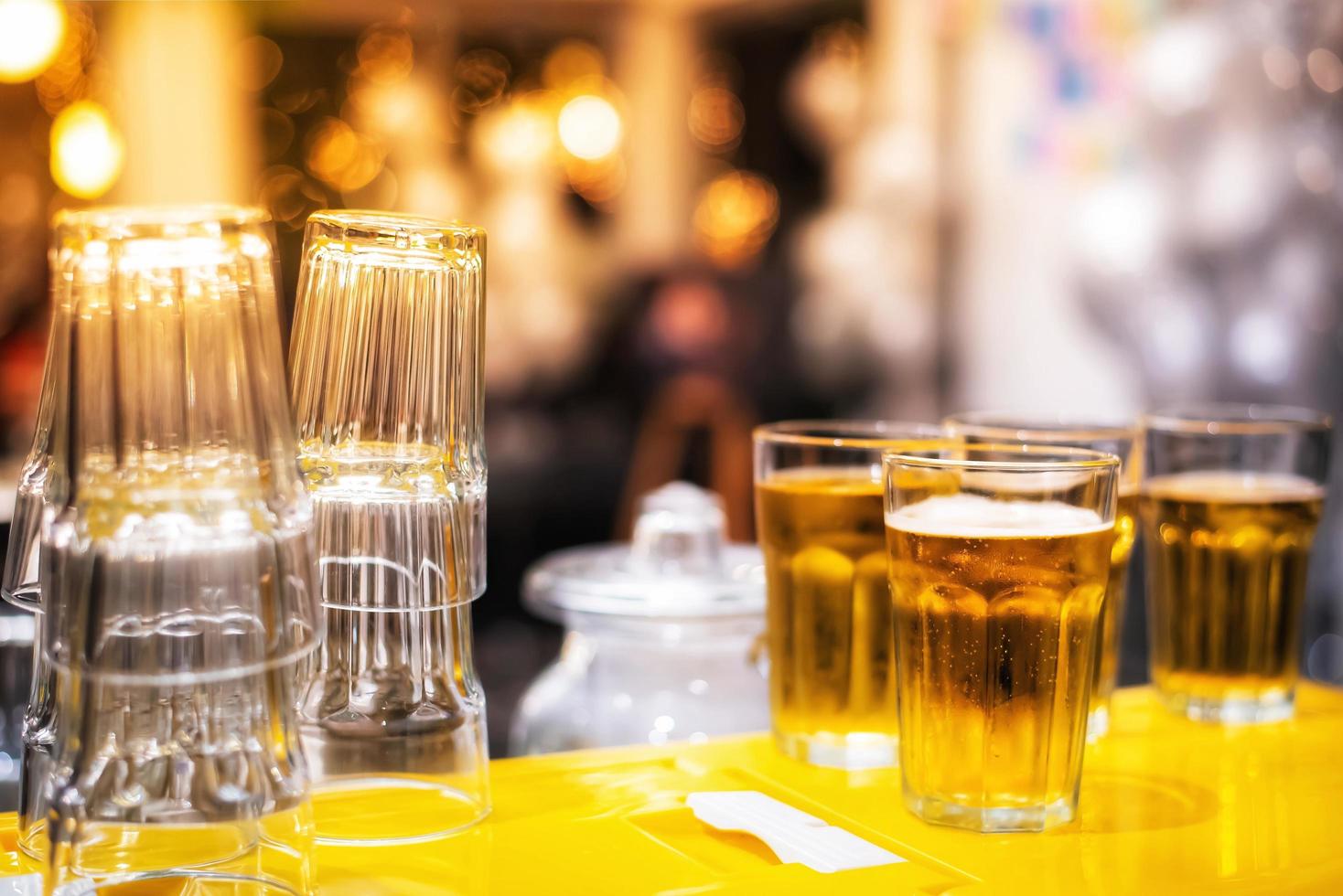 la cerveza en el vaso vertido está lista para ser servida y el vaso vacío boca abajo en el bar en un fondo borroso en el restaurante. foto