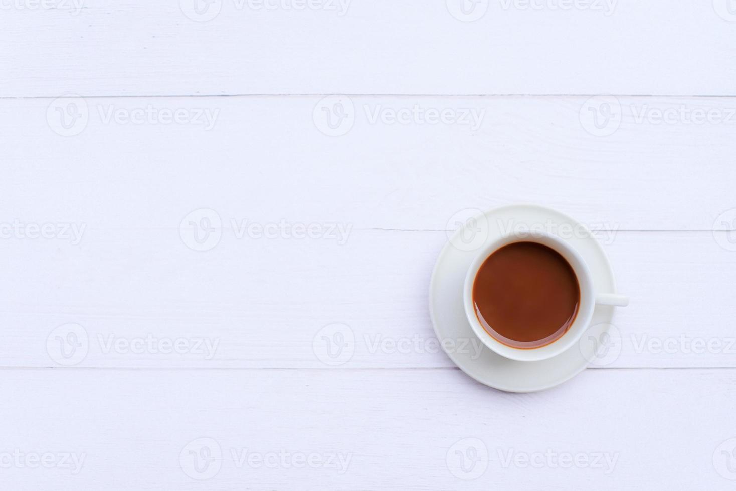 imagen superior de un café con leche caliente en una taza blanca sobre una mesa de madera blanca con espacio de copia foto