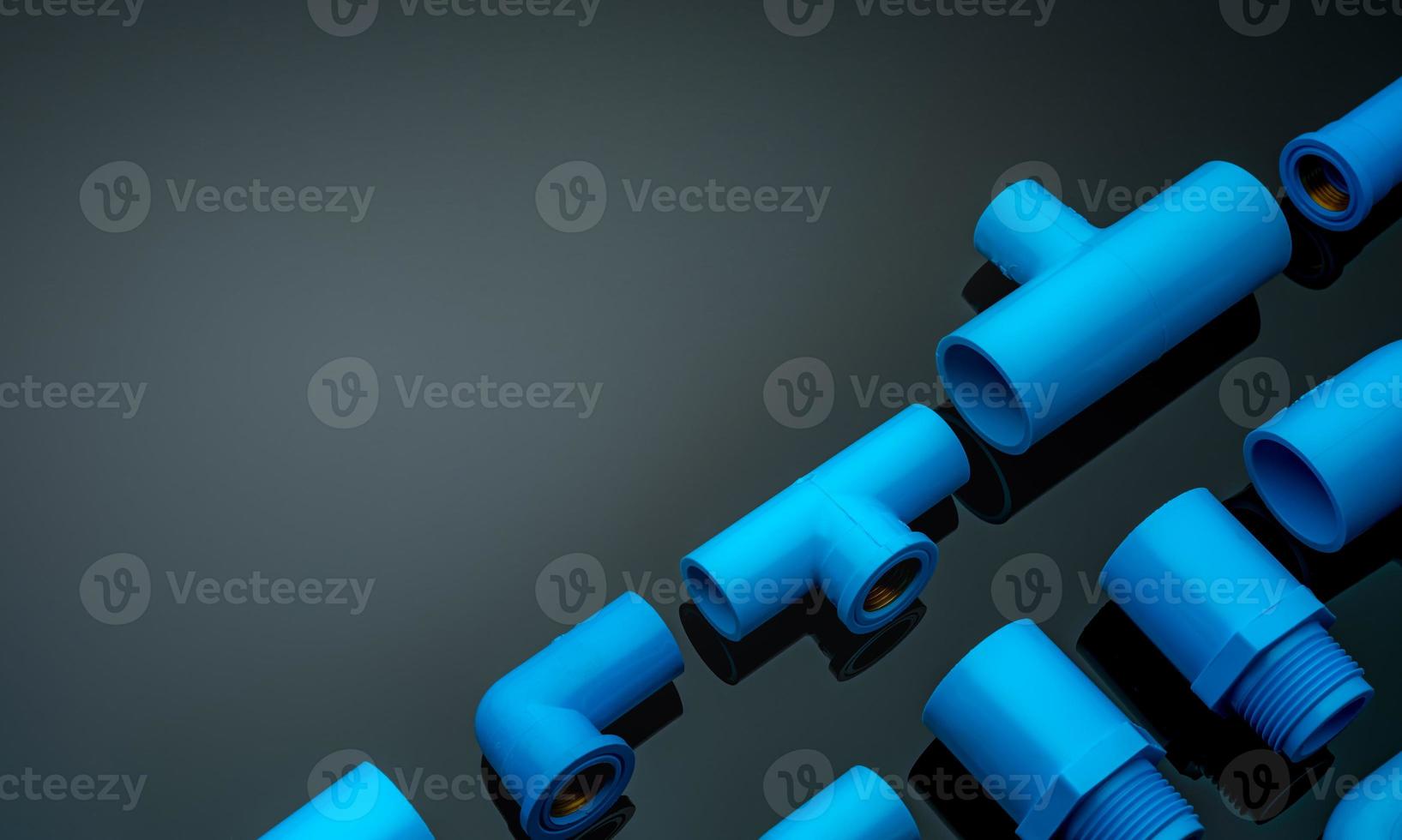 Set of blue PVC pipe fittings isolated on dark background. Blue plastic water pipe. PVC accessories for plumbing. Plumber equipment. Bend and three way connection plastic pipe for water drain sewage. photo