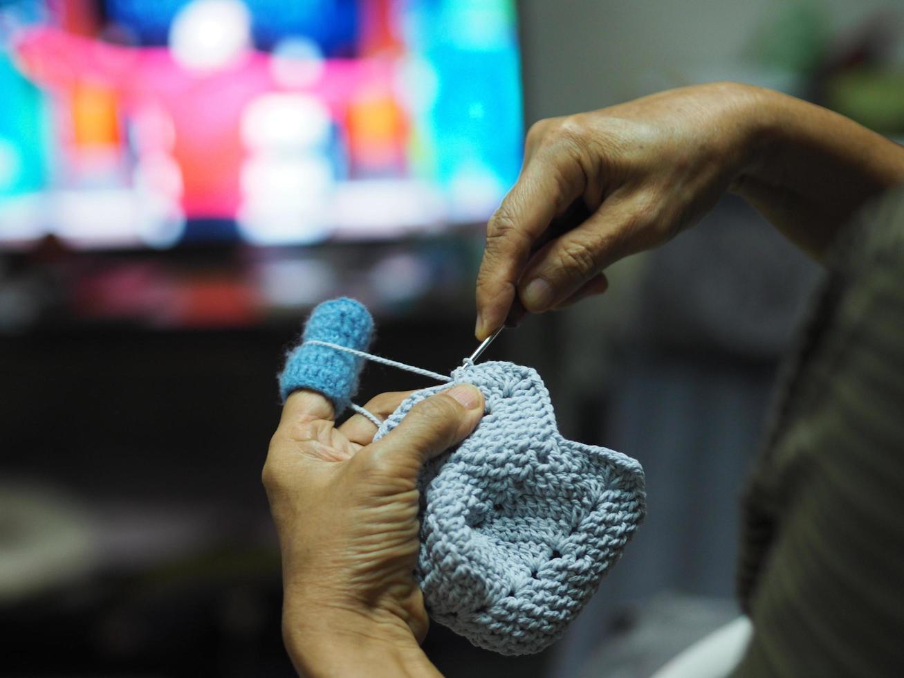 Woman hand knitting blue yarn handmade DIY hobby watching television TV photo