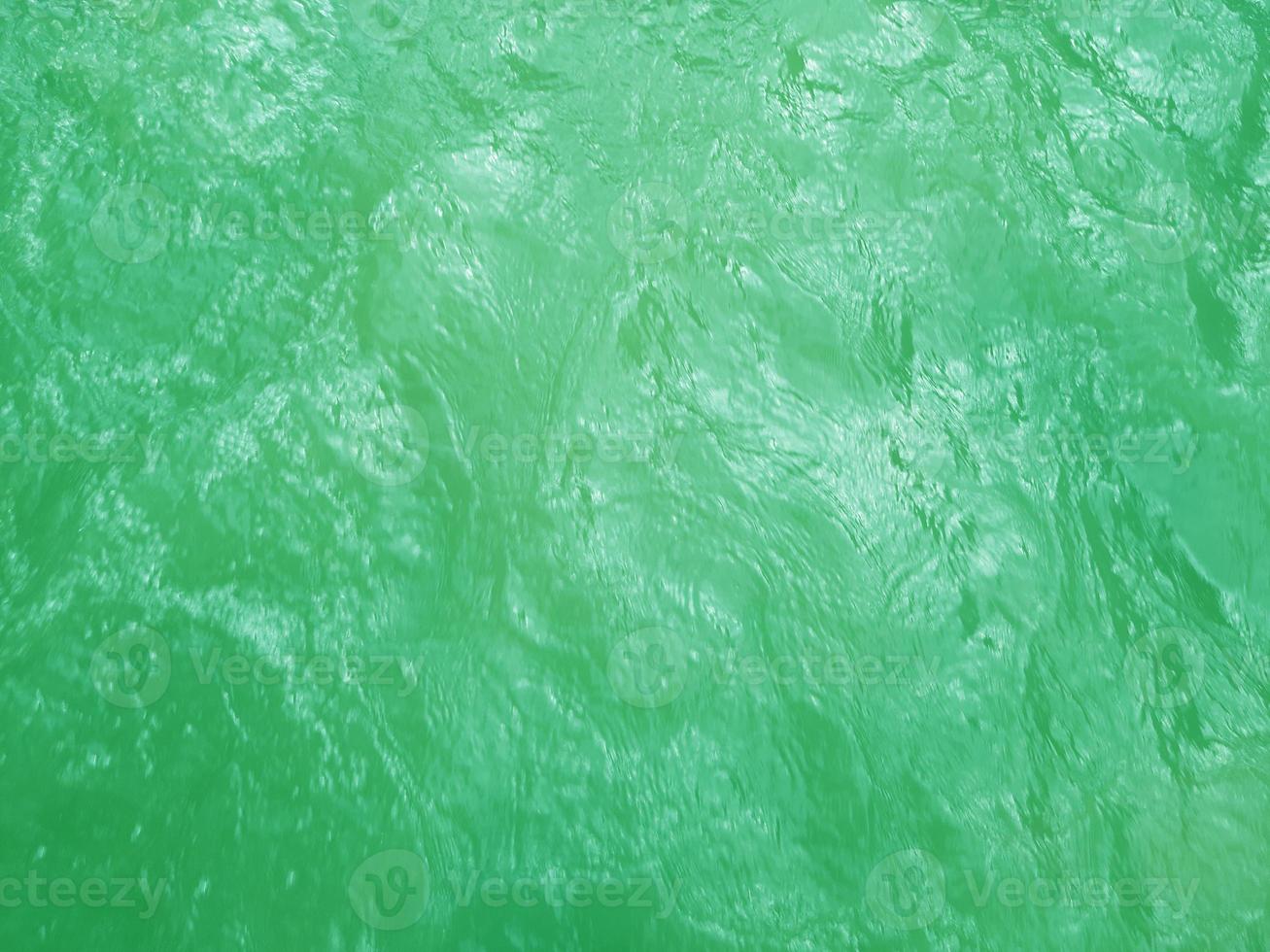 Defocus blurred transparent green colored clear calm water surface texture with splashes and bubbles. Trendy abstract nature background. Water waves in sunlight. Green water background. photo