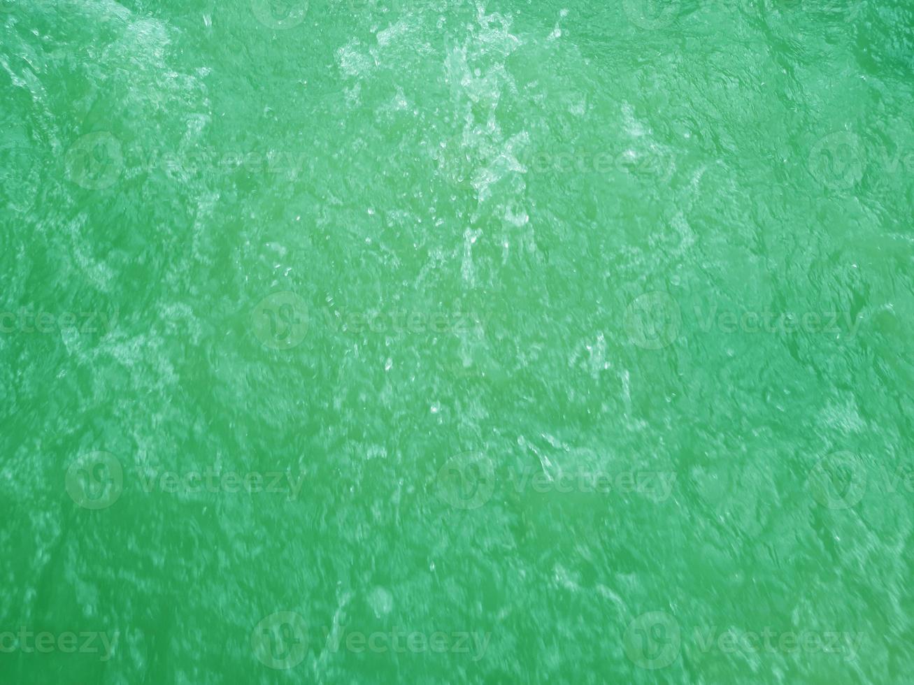 Defocus blurred transparent green colored clear calm water surface texture with splashes and bubbles. Trendy abstract nature background. Water waves in sunlight. Green water background. photo