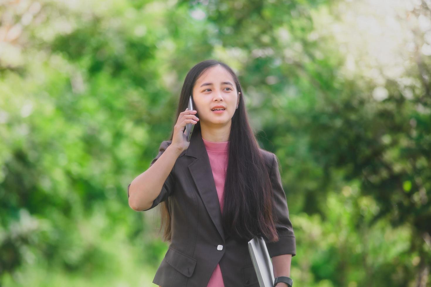 business woman Standing on the phone in the park beside the town photo