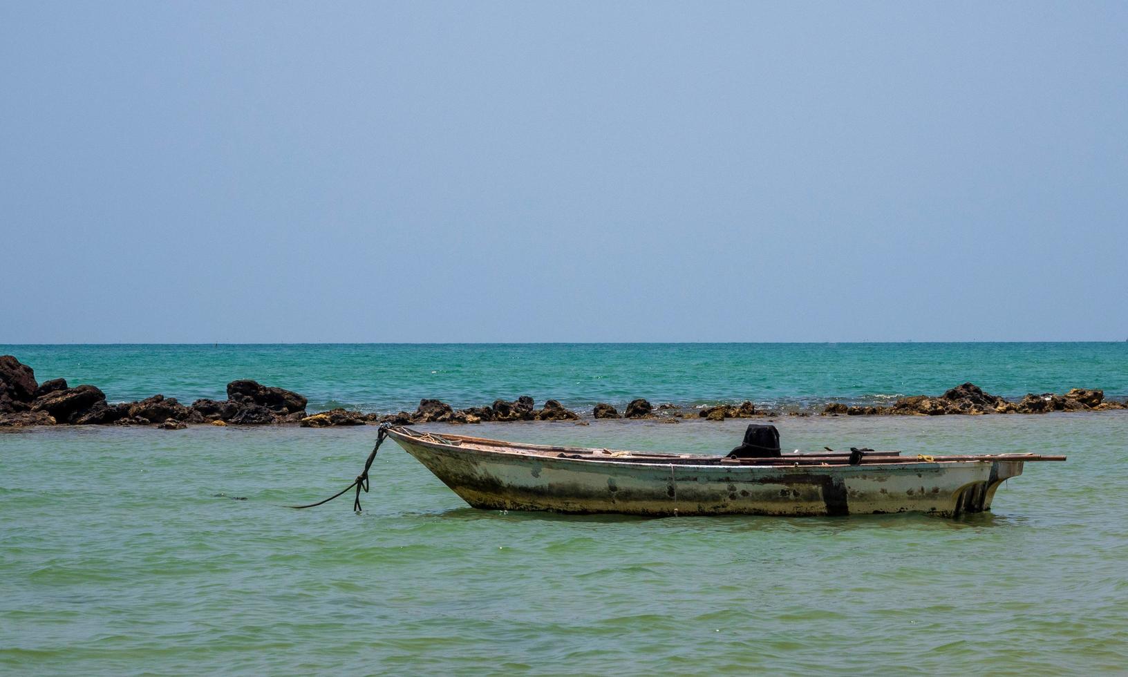 paisaje mirada vista pequeño barco de pesca de madera antiguo estacionado costa el mar. después de la pesca de los pescadores en el pequeño pueblo es pequeña pesca local. cielo azul, nubes blancas, clima despejado, playa phala, rayong foto