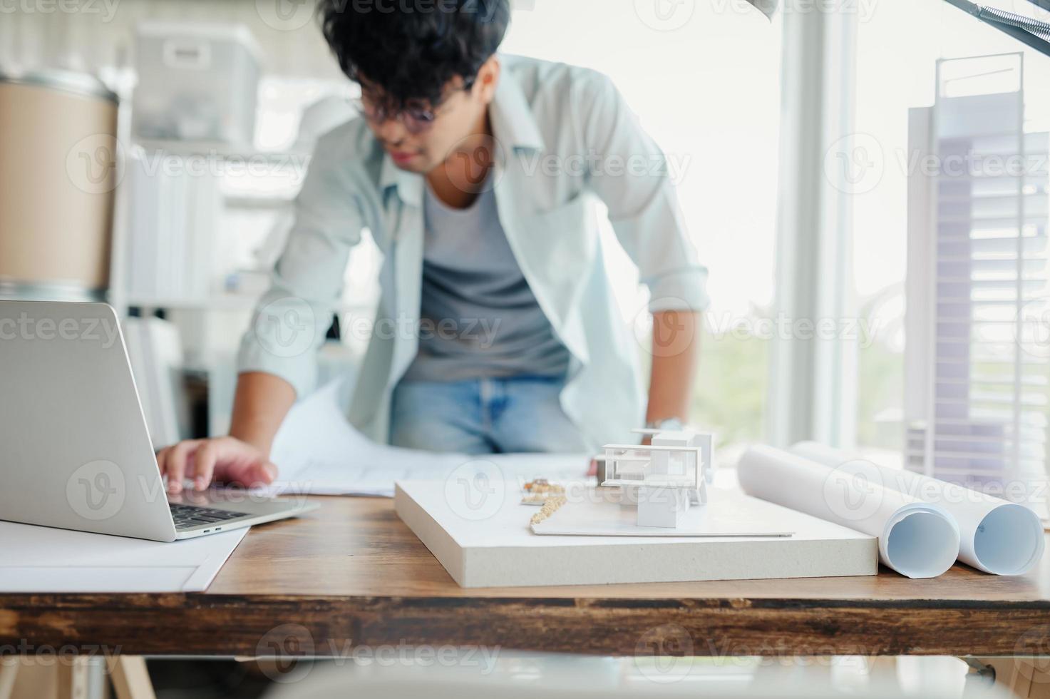 enfoque selectivo, arquitecto o ingeniero asiático que actualmente está considerando materiales para diseñar condominios modernos. arquitecto o ingeniero asiático se sienta y analiza, diseña proyectos en la oficina. foto