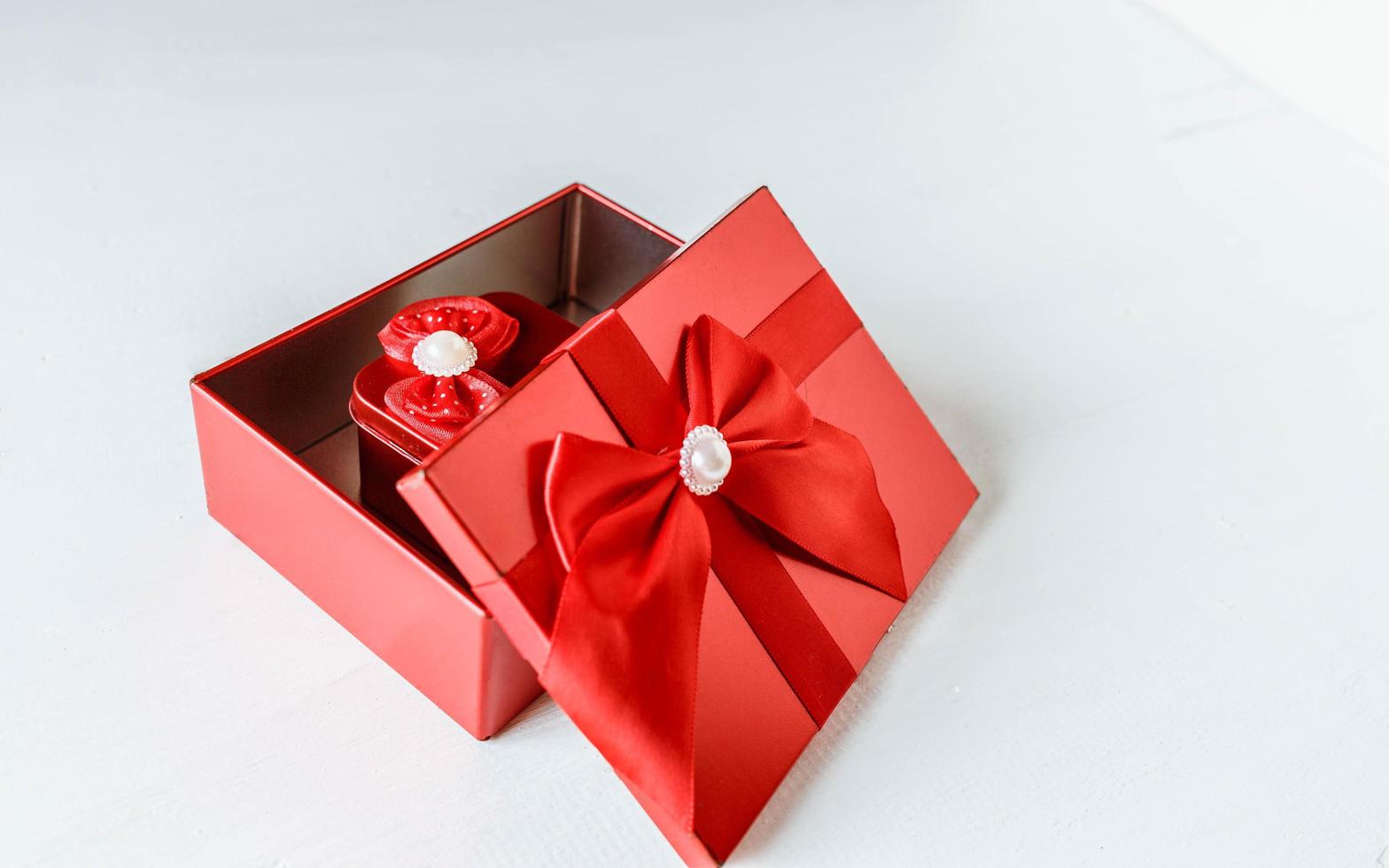 Red gift box  opened on white wooden table photo