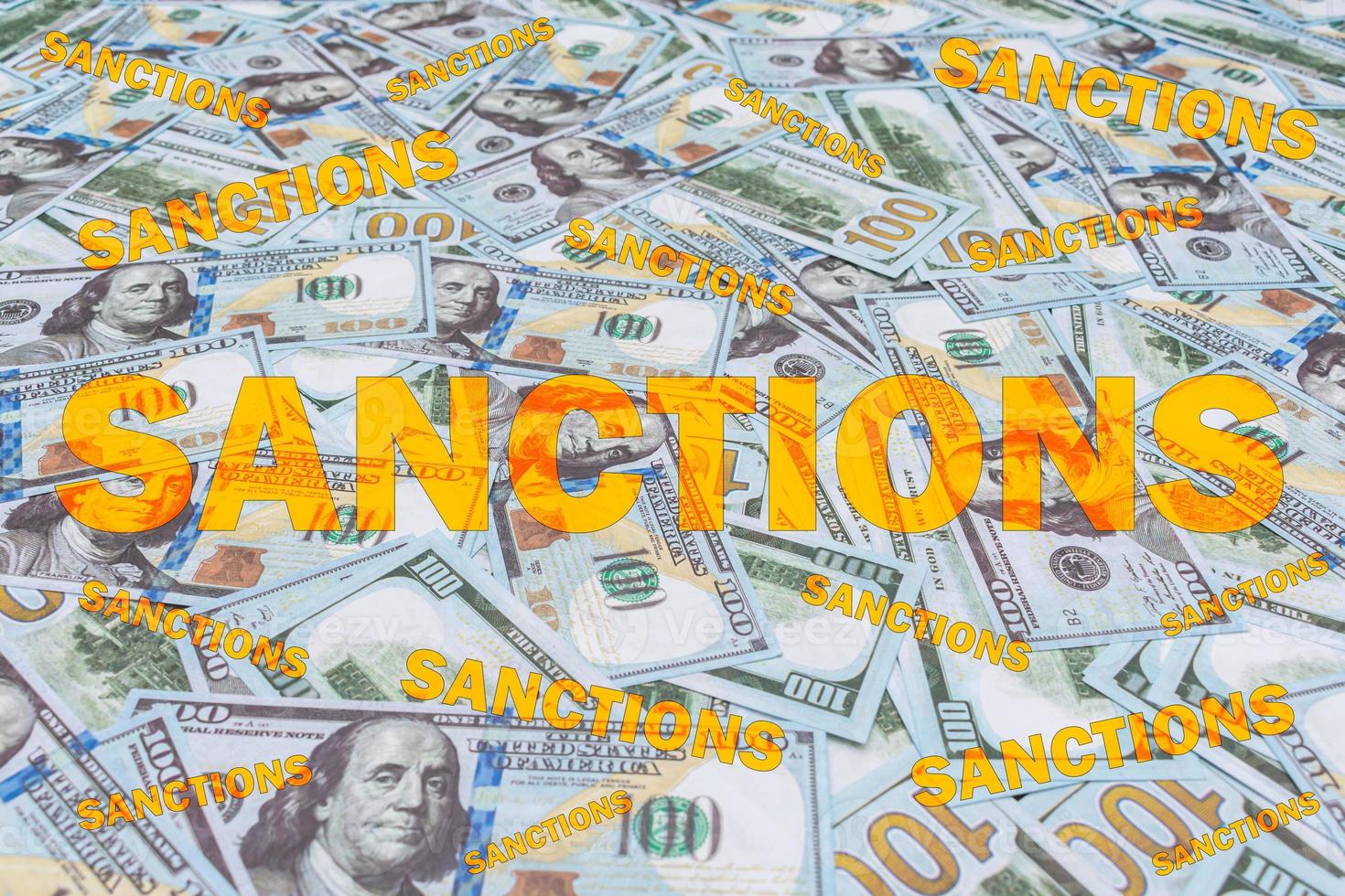 Sanctions word on the background of many hundred dollar bills photo