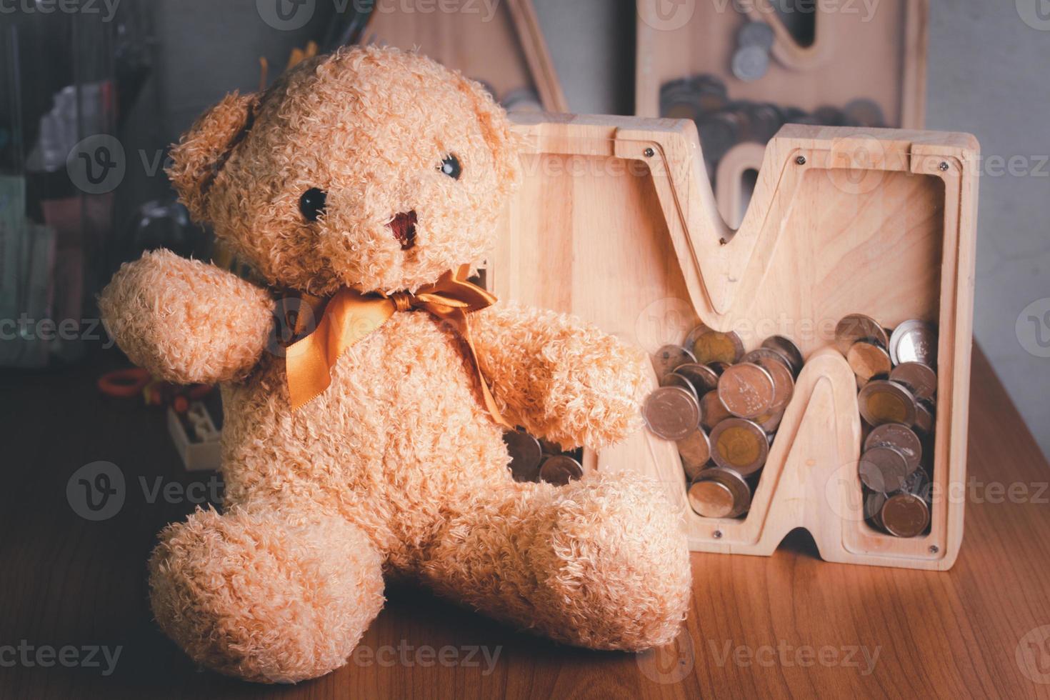 Wooden piggy bank with brown teddy bear. Money saving concept. Vintage picture style. photo