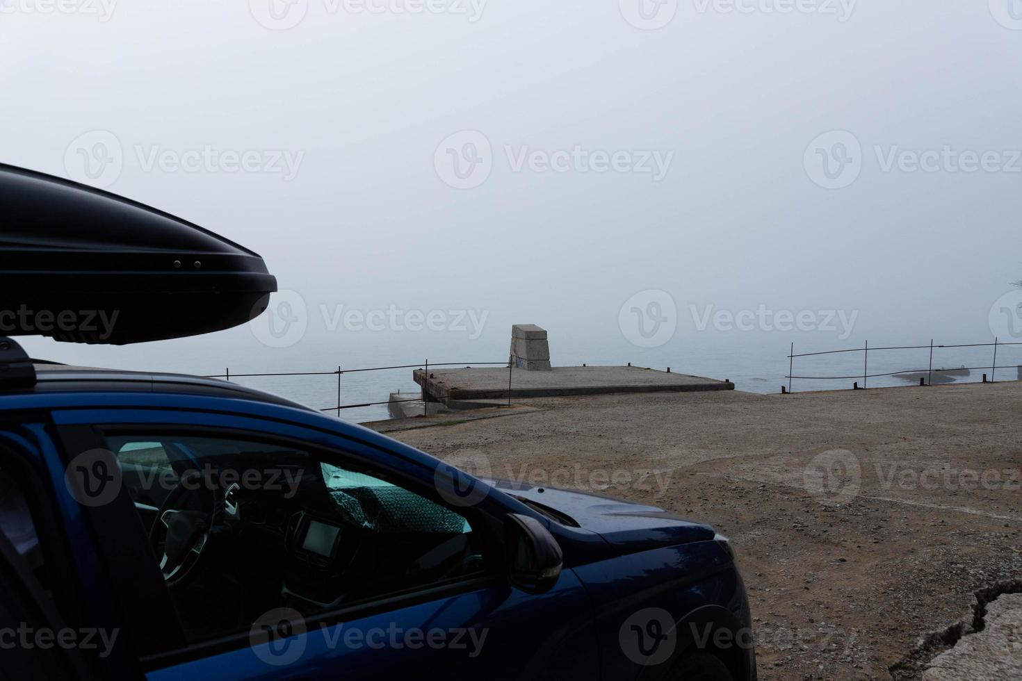 Travel to the sea by car. Crossover with roof rack stands against the background of the sea. photo