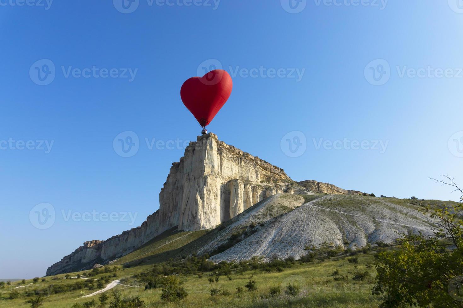 Hot air balloon, Red balloon in the shape of a flying heart against the background of the White Rock. photo